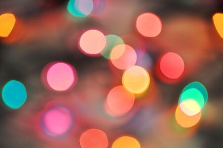Glowing and festive colored light circles created from in camera and lens bokeh. Christmas fairy lights defocused giving a blurred effect. Background for design.の写真素材