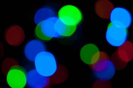 Glowing and festive colored light circles created from in camera and lens bokeh. Christmas fairy lights defocused giving a blurred effect. Background for design.の写真素材