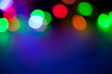 Glowing and festive colored light circles created from in camera and lens bokeh. Christmas fairy lights defocused giving a blurred effect. Background for design.の写真素材