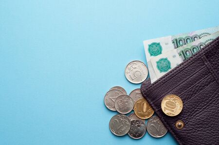 Russian rubles in the wallet on a blue background. Thousand notes and various coins.