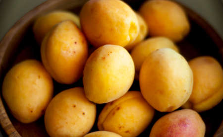 Juicy tasty apricots on a wooden plate, soft focus.の写真素材