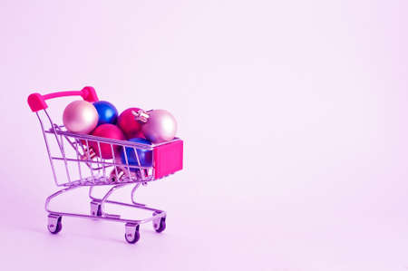 Pink basket with colored christmas balls. Christmas shopping theme. Place for textの写真素材