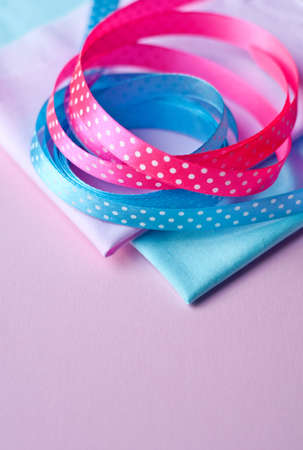 Cotton fabric of different colors and satin ribbons with polka dots on a pink background. Space for text, top viewの写真素材