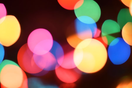 Glowing and festive colored light circles created from in camera and lens bokeh. Christmas fairy lights defocused giving a blurred effect. Background for design.の写真素材