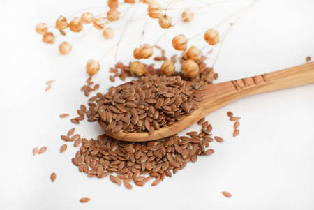 Flax seeds in a wooden spoon on whiteの写真素材