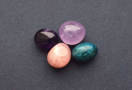 Multi-colored gemstones, cut tumbling stones. Amethyst, rose quartz, apatite on a gray background.の写真素材