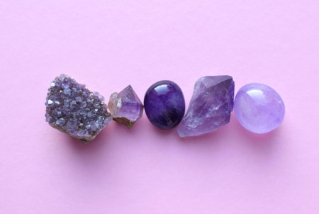 Gemstone minerals on a pink background. Round tumbling minerals of amethyst and amethyst crystal.の写真素材
