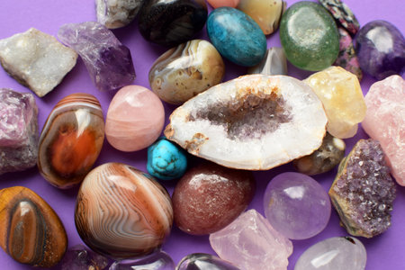 Gems of various colors. Geode amethyst, rose quartz, agate, apatite, aventurine, olivine, turquoise, aquamarine, rock crystal on purple backgroundの写真素材