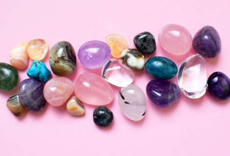 Gems of various colors. Amethyst, rose quartz, agate, apatite, aventurine, olivine, turquoise, aquamarine, rock crystal on pink backgroundの写真素材
