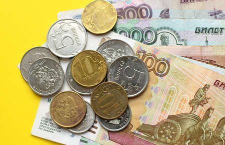 Russian rubles on a yellow background. Banknotes and various coins.
