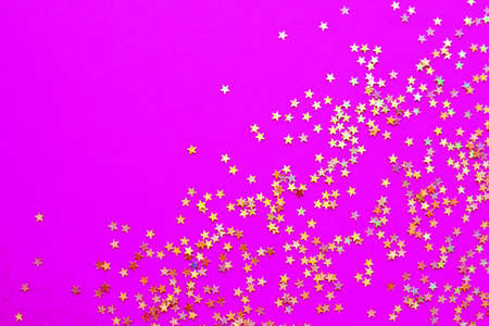 Background of shiny golden small stars on a fuchsia background. Selective focus. Christmas concept. Glitter texture.の写真素材