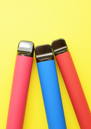 Three electronic cigarettes on a yellow background. Place for your text.の写真素材