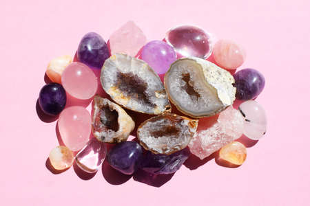 Beautiful gemstones, amethyst geode and druze of natural purple mineral amethyst on a pink background against a bright light. Amethyst and rose quartz. Large crystals of semi-precious stones.の写真素材