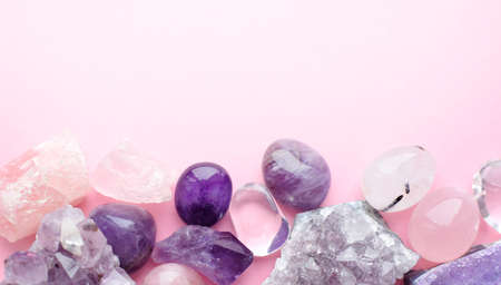 Beautiful gemstones and druses of natural purple mineral amethyst on a pink background. Amethysts and rose quartz. Large crystals of semi-precious stones.の写真素材