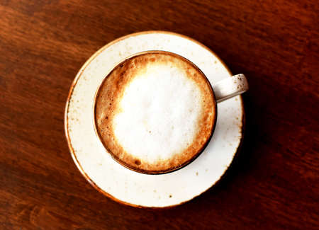 Cappuccino coffee in a beautiful ceramic cup on a wooden table in a cafe. A cup of coffee. Top viewの写真素材