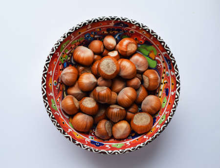 Hazelnuts on a beautiful red painted plate. Hazelnuts in shell, healthy foodの写真素材
