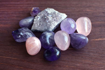 Beautiful gemstones, geode amethyst and druses of natural purple mineral amethyst on a wooden background. Amethysts and rose quartz. Large crystals of semi-precious stones.の写真素材