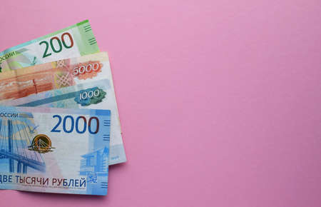 Russian rubles on a pink background. Thousand notes and various coins. Copy space.