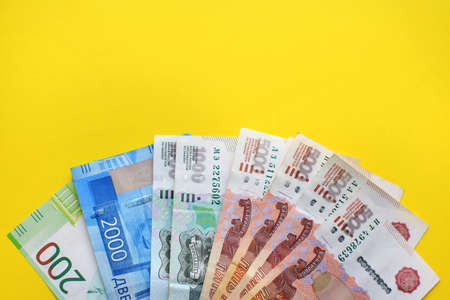 Money of Russia. Banknotes and coins on yellow background. Close-up of Russian rubles of various denominations. Finance concept. Copy spaceの写真素材
