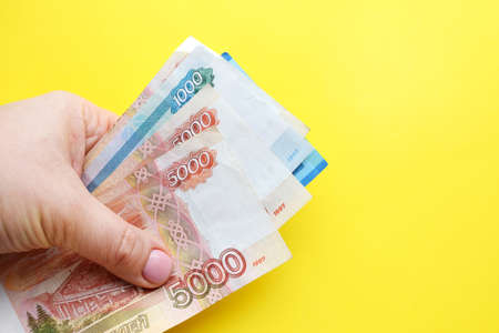 Russian ruble banknotes in a female hand on a yellow background. Copy space.の写真素材