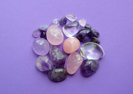 Gemstone minerals on a purple background. Round tumbling minerals of amethyst and amethyst crystal.の写真素材