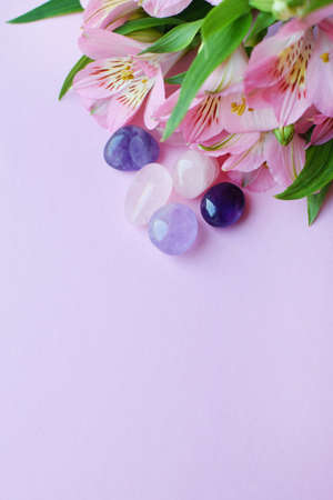 Beautiful pink alstroemeria flowers and semi-precious stones rose quartz and amethyst lie on a pink background.の写真素材