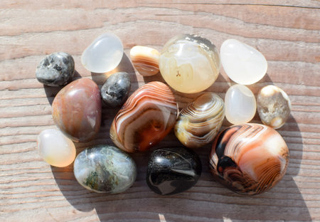 Multicolored gemstones, tumbled minerals. Bostwan agate of various sizes on a wooden background.の写真素材