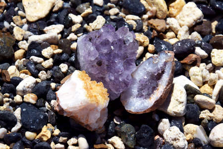 A beautiful druse and geode of amethyst and druse of citrine lie on wet stones on the seashore. Crystals of semi-precious stones in the sun.の写真素材
