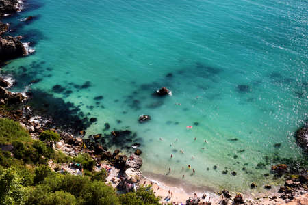 Lots of people swimming in the clear turquoise sea. Summer seascape, beach, beautiful waves, blue transparent water. People enjoying swimming in the sea. view from above.の写真素材