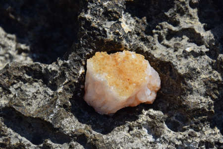 A beautiful druse citrine lies on a stone. Intergrowth of yellow crystals of semi-precious quartz in bright sunlight.の写真素材