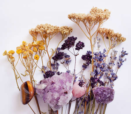Wild dry herbs and semi-precious crystals of amethyst and rose quartz lie on the table. Magic amuletsの写真素材