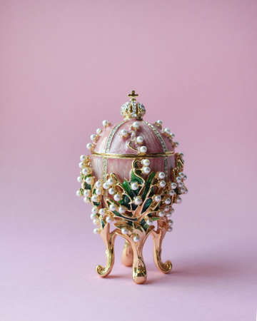 A traditional Russian souvenir in the Faberge style, an enamel pink gilded egg adorned with precious crystals and pearls, a copy of the famous Faberge egg "Lilies of the valley".の写真素材