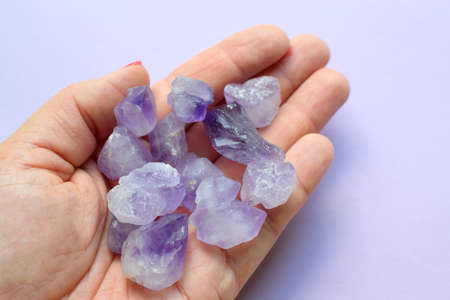 Beautiful semi-precious stones in a female hand. A woman holds purple amethyst crystals in her hands. Magic stones for meditation.の写真素材