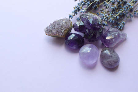 Beautiful amethyst stones and amethyst druze with a dry bouquet of lavender on a lilac background. Magic amulets. copy spaceの写真素材