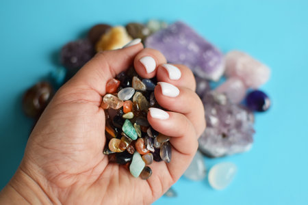 Beautiful multi-colored semi-precious stones in a female hand against the background of other precious stones. selective focus.の写真素材