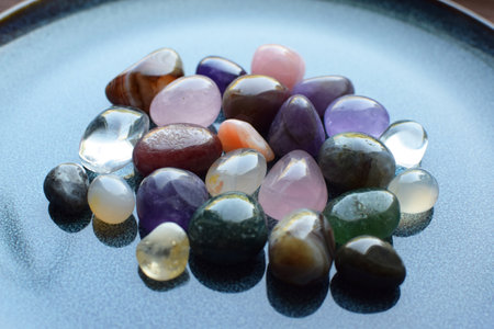 Gemstones of different colors. Amethyst, rose quartz, agate, apatite, aventurine, olivine, turquoise, aquamarine, rock crystal on a blue ceramic plate.の写真素材
