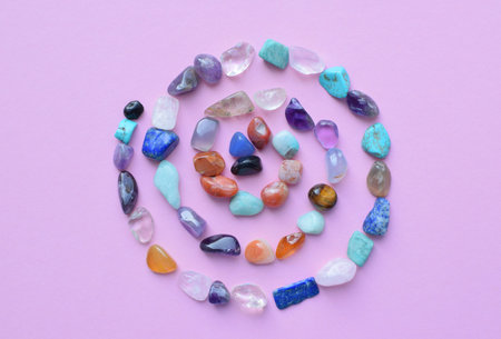 A spiral of semi-precious minerals on a pink background. Healing crystals.の写真素材