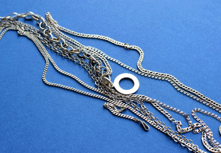 Different silver chains lie on a blue background. Jewelry for women and menの写真素材