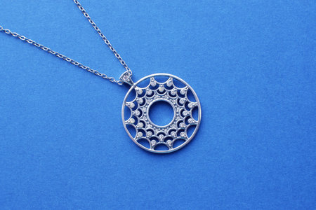 Clone pendant in the shape of a circle with sparkling sterling silver cubic zirkonia on a chain. Beautiful jewelry for a woman. Jewelry decoration on a blue background.の写真素材