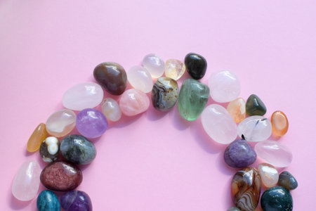 The circle is lined with natural minerals. Semi-precious stones of different colors, raw and processed. Amethyst, rose quartz, agate, apatite, aventurine on a pink background.の写真素材
