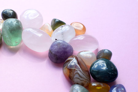 Semi-precious beautiful stones of bright colors lie on a pink background. Amethyst, rose quartz, agate, apatite, aventurine, olivine, turquoise, aquamarine, rock crystal on a pink background. selective focus.の写真素材