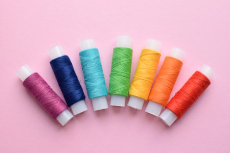 Sewing colored threads on a pink background. Cotton threads in spools.の写真素材