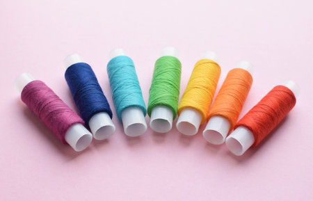 Sewing colored threads on a pink background. Cotton threads in spools.の写真素材