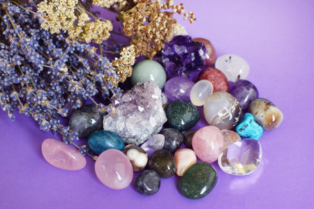 Semi-precious stones of different colors with dry lavender bouquet. Amethyst and amethyst druse crystals, rose quartz, agate, apatite, aventurine, turquoise, rock crystal on a purple background.の写真素材