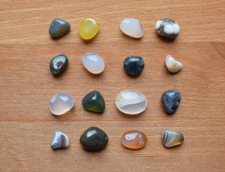 Semi-precious stones of different colors. Round agate stones are laid out in rows on a wooden background.の写真素材