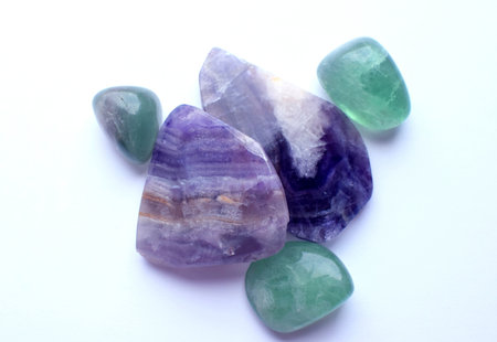 Sections of beautiful striped purple fluorite and green fluorite stones close up on a white...
