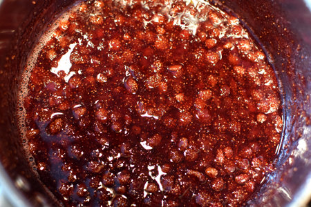 The process of making homemade strawberry jam. Wild strawberries are boiled in sugar syrup in a metal pan.の写真素材