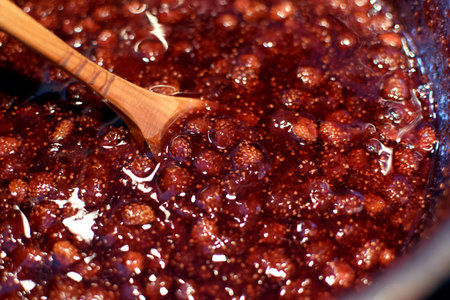 Making strawberry jam at home. Wild strawberry jam is boiled in a saucepan and stirred with a wooden spoonの写真素材