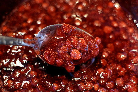Making strawberry jam at home. Wild strawberries are boiled with sugar syrup and stirred with a metal spoonの写真素材