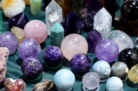 Beautiful balls and obelisks of aquamarines, rose quartz and amethysts at the stone exhibition. Natural stones of rock crystal, charoite and amazonite at the stone fairの写真素材